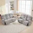 A blurry image of a gray reclining sofa set with cup holders in a living room.